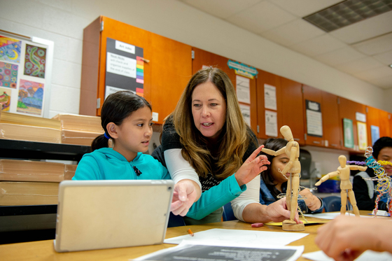 Art teacher and student looking at laptop in classroom