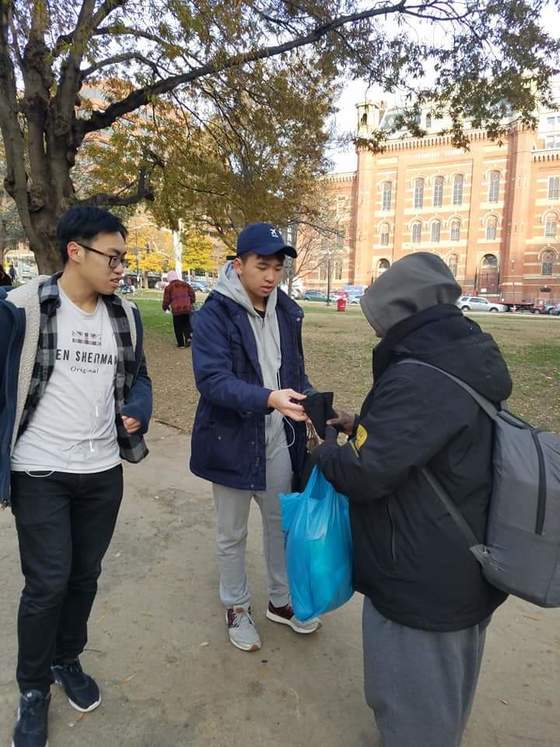 Picture of students giving items to homeless person
