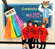 students standing in front of bulletin board with creativity starts here and willow the fox