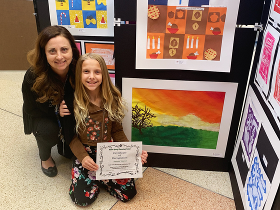 art teacher and student with certificate showcasing artwork