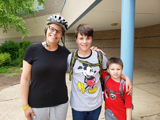 mom with her two sons on bike to school day