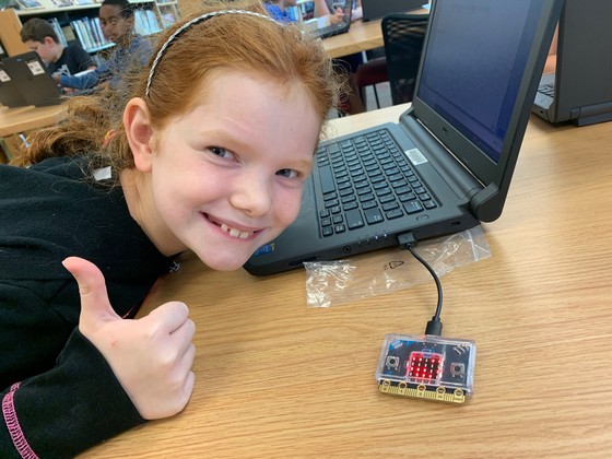 A fourth grade student gives a big thumbs up as she works on a laptop in the Clermont library.
