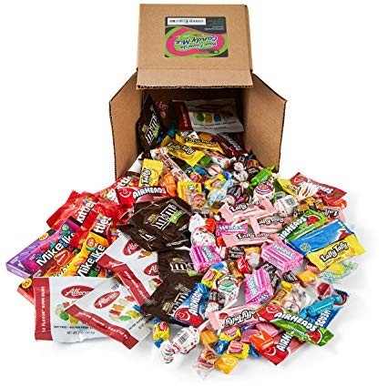 An image shows a cardboard box on its side with a variety of candy spilling out. 