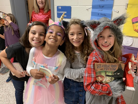 Students dressed as storybook characters pose with their books. 