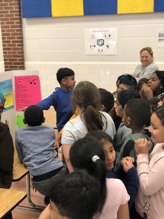 Photo of students looking at third grade ladybug exhibits