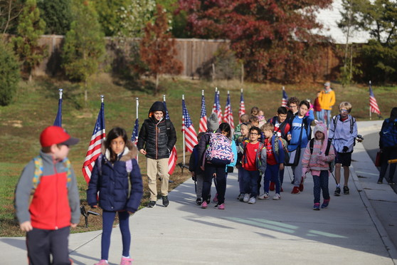 Students arriving at school walk by a row of US flags lining Clermont's front sidewalk.