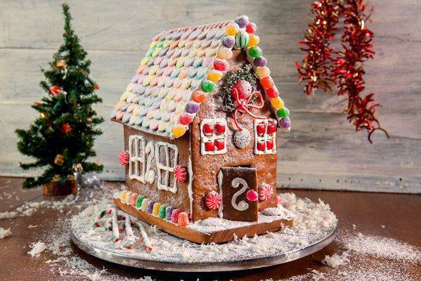 A photo shows a gingerbread house decorated with candies and frosting. 