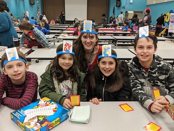 teacher playing headbands with students at game night 