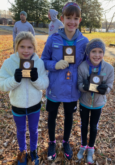 Students from the Run Club display small plaques from the recent 5K.
