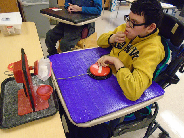 Student using a switch to help pour detergent