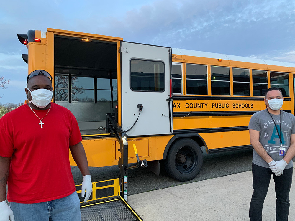 Bus drivers wearing face masks in front of a bus