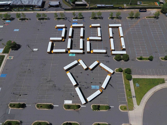 FCPS buses in an empty lot positioned to spell "2020" and form the shape of a heart.