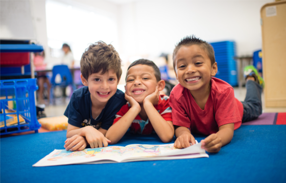 Three pre-k students smiling at the camera