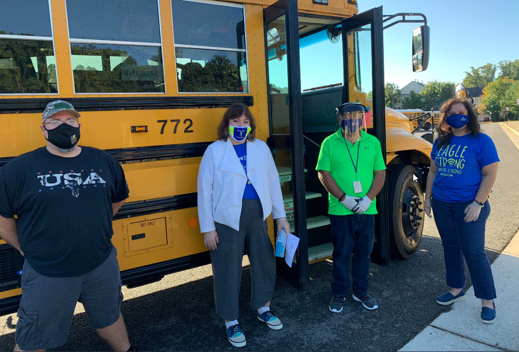 Eagle View ES bus drivers and principal wearing masks in front of a school bus.