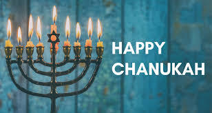 Happy Chanukah! A lit menorah stands in front of a teal wooden background.
