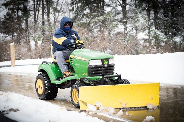 Custodian riding tractor in the snow