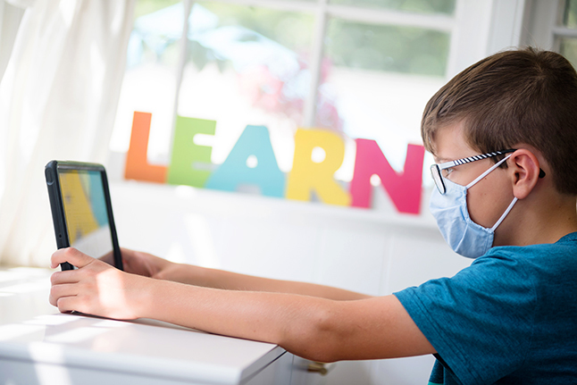 photo of male student looking at ipad with the word LEARN in background