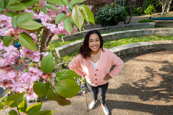 photo of female student smiling with cherry blossoms in background