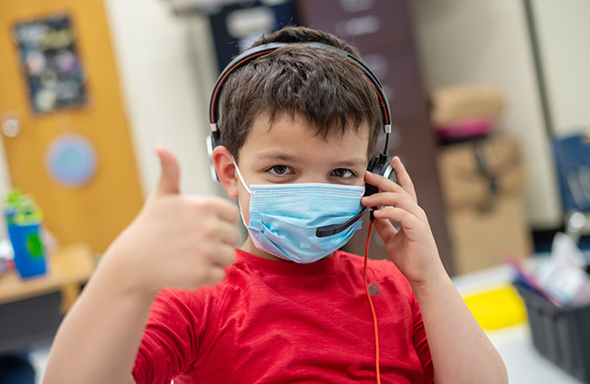 photo of male student with mask giving a thumbs up