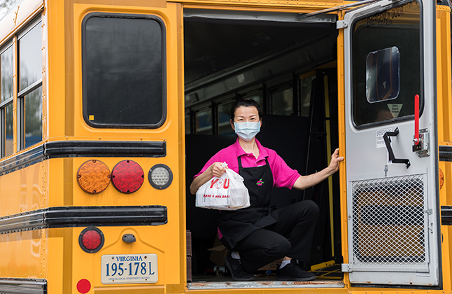 Food service worker giving out meals on a bus.