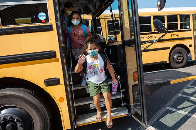 Elementary students getting off a school bus.