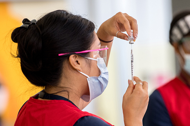Nurse preparing a medical needle for a vaccination