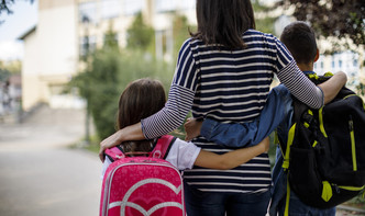 parent with arms around two children with facing away from the camera 