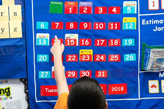 photo of boy pointing at a calendar in class