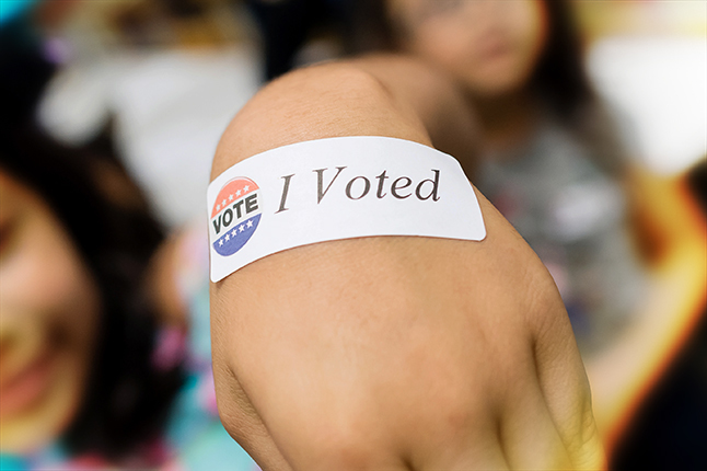 Hand with a I Voted sticker.