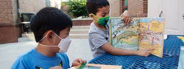 Picture of students reading outside while wearing masks