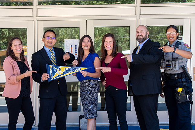photo of Thoreau MS admin team with SRO pointing at school pennant
