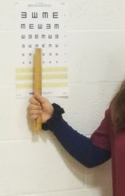 Eye chart with student pointing to the letters
