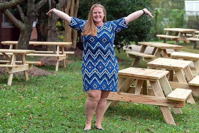Assistant Principal Meghan Ehrman with arms outspread showing her picnic table project