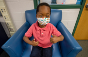 Picture of elementary student wearing mask with thumbs up