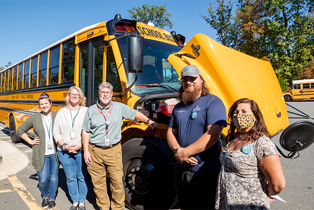 photo of bus drivers in front of an electric bus