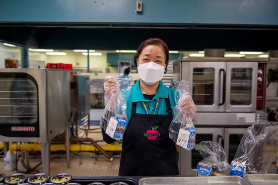 Cafeteria worker holding up meal kits.