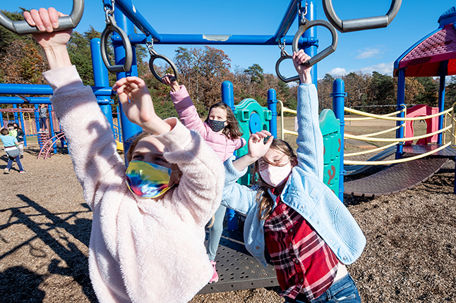 Students playing on a jungle gym with warm coats on. 