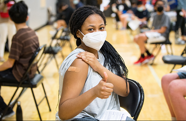 Girl with band aid on her arm getting a covid shot. 
