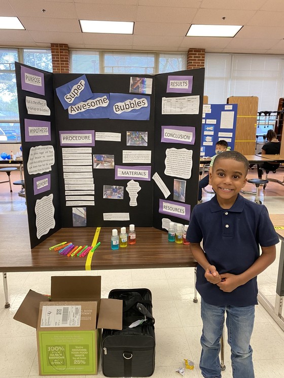 Photo of a student smiling in front of his science project
