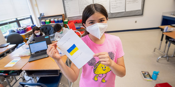 Freedom Hill Elementary student holding up a drawing of the Ukrainian flag. 