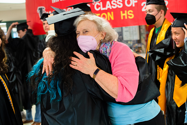 Teacher hugs student in graduation gown