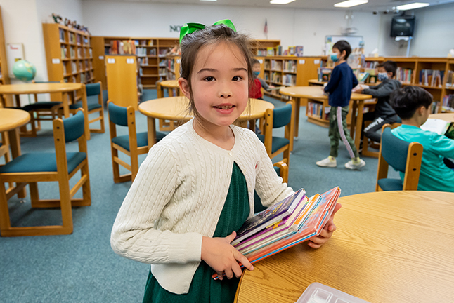 Young student holds a stack of library books