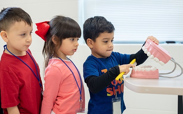 Students in line waiting to practice brushing large fake teeth.  