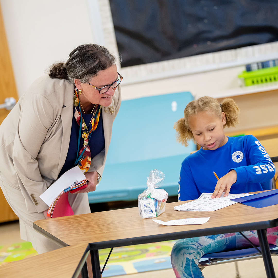Superintendent Dr. Michelle Read talks with a student looking over a paper. 