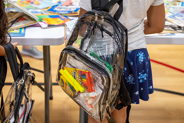 Girl stands wearing backpack of school supplies