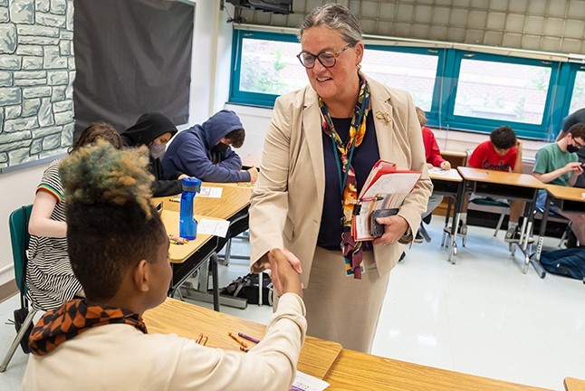 Dr. Reid shaking hands with a student in a classroom