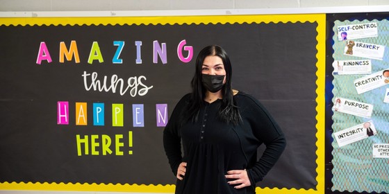 teacher standing in front of a bulletin board