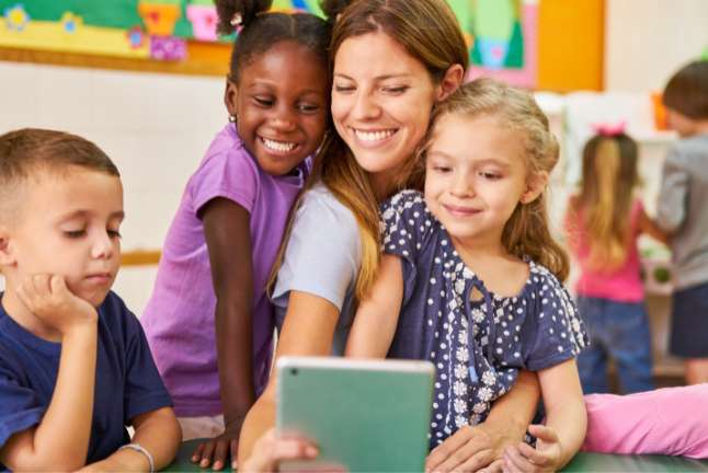 A teacher and three young students look at an ipad