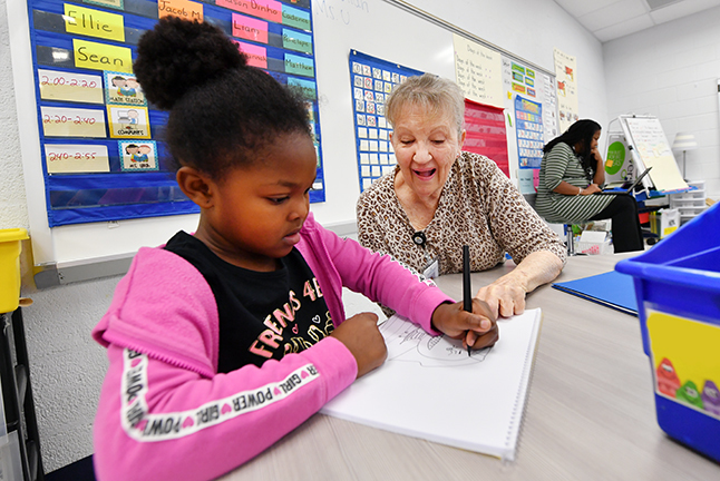 A community member volunteering in a school and supporting students.