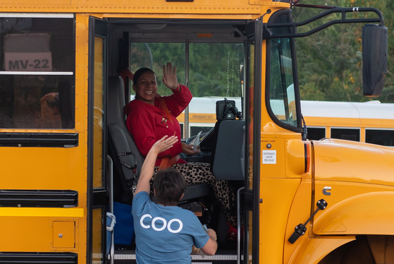A bus driver waves at a member of leadership delivering baked goods